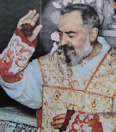 Padre Pio raises his hand to bless the congregation of a public Mass, his brown fingerless glove soaked with blood from the stigmata visible.